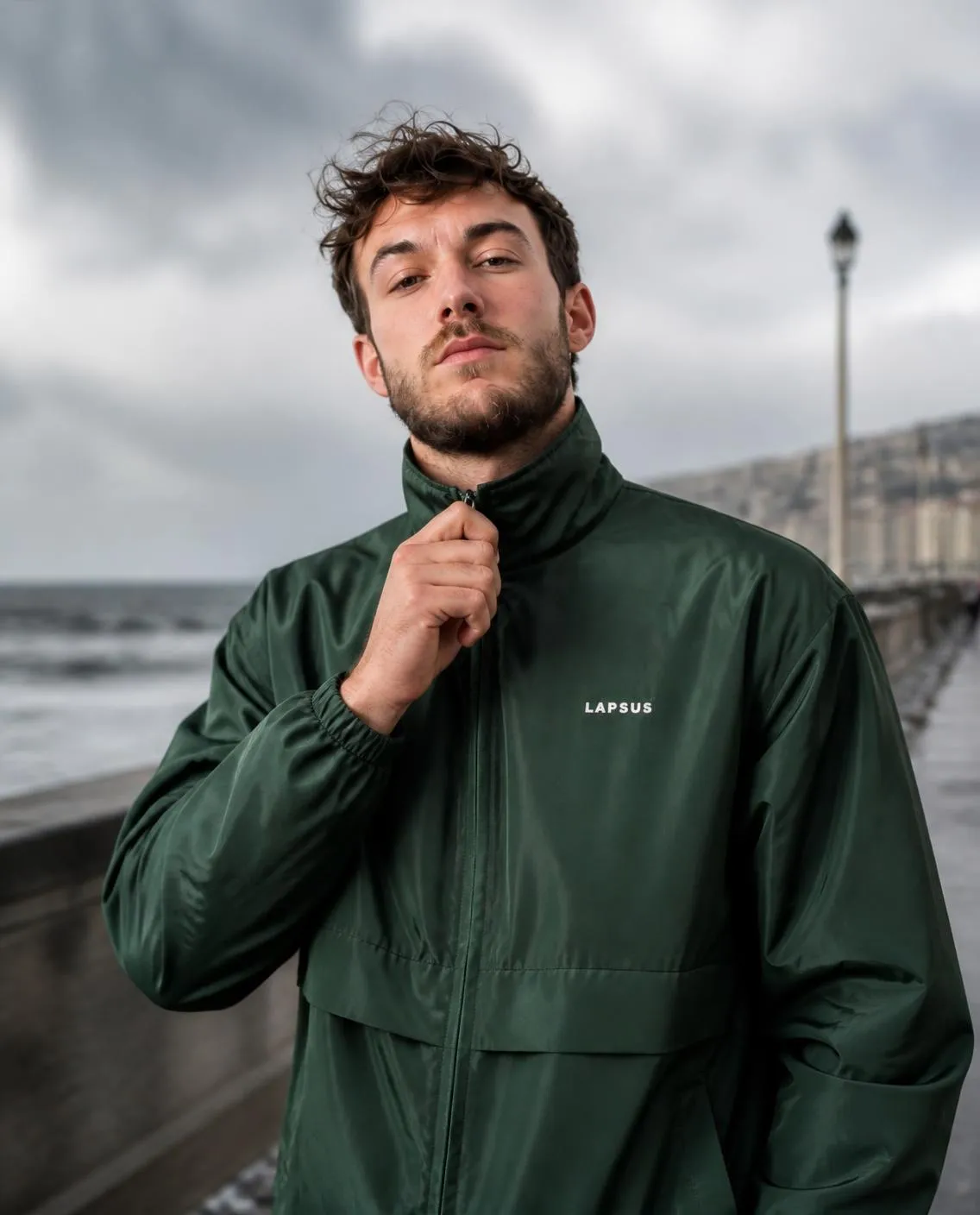 Green windbreaker, collar up, seaside