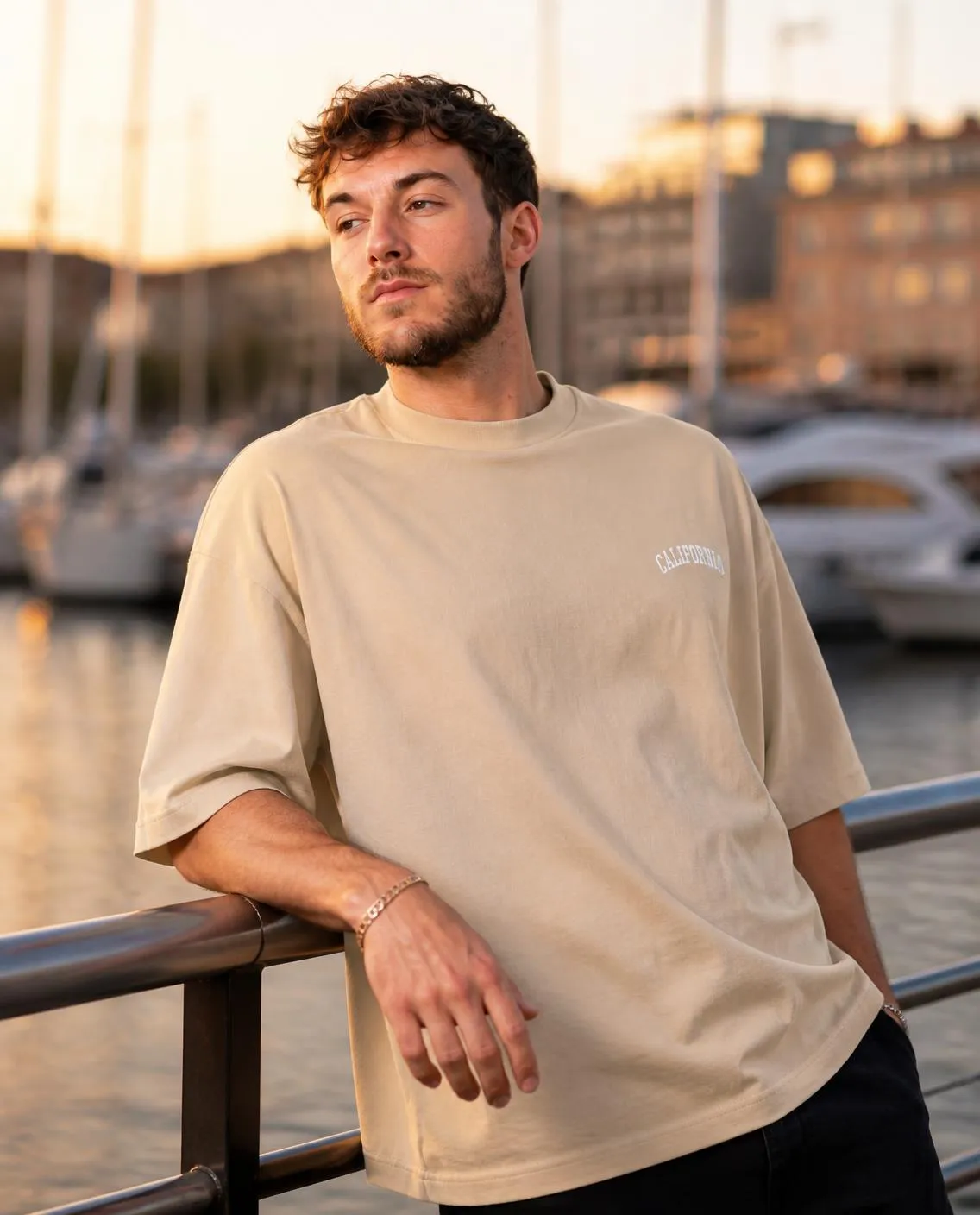Cream T-shirt leaning on the harbour railing